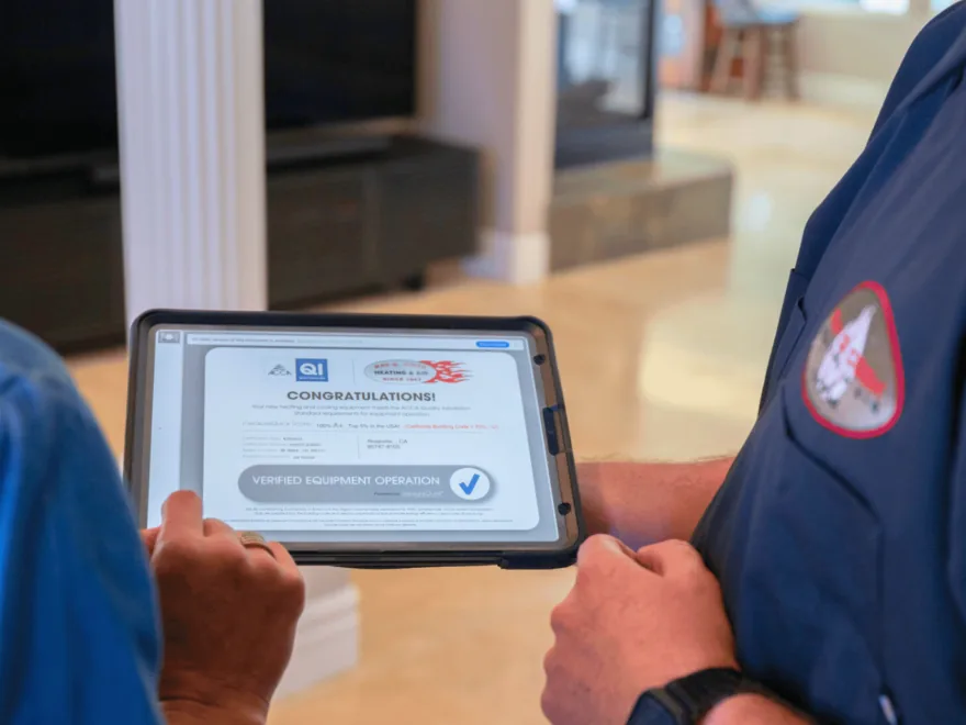 A homeowner and technician reviewing an ACCA Quality Installation 'Verified Equipment Operation' result on a tablet — the same measurement documenting compliance.