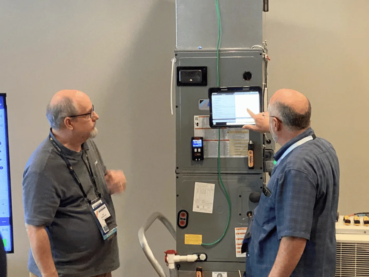 One measureQuick technician explaining an HVAC system to another at the equipment.