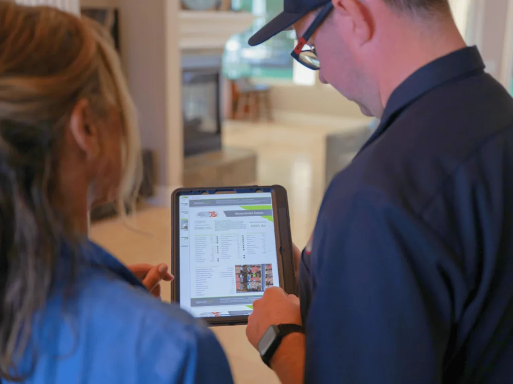 Technician and homeowner reviewing a measureQuick report on a tablet