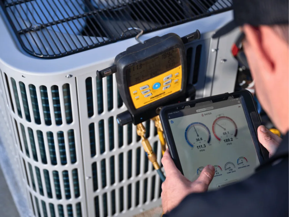 Technician using the measureQuick app on a tablet at an outdoor condenser