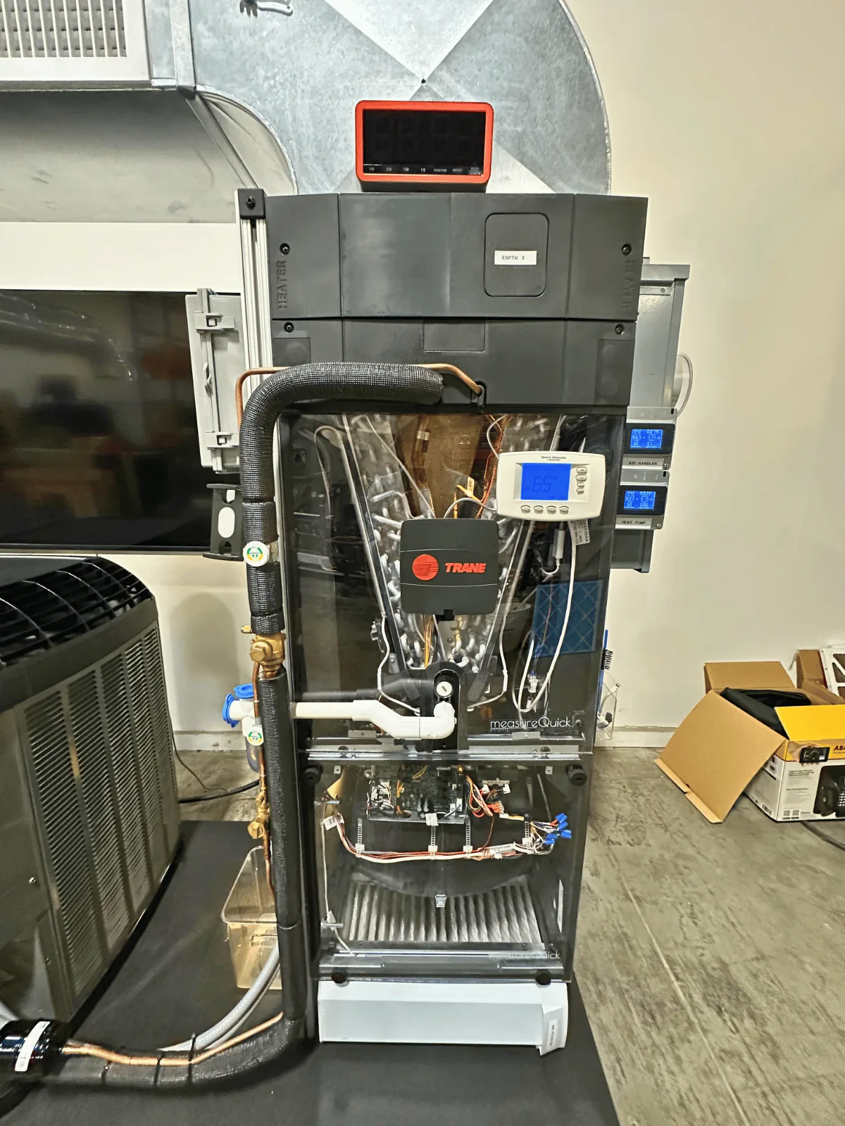 The air handler with its clear viewing door open, showing the coil, blower, and the measureQuick display mounted on top