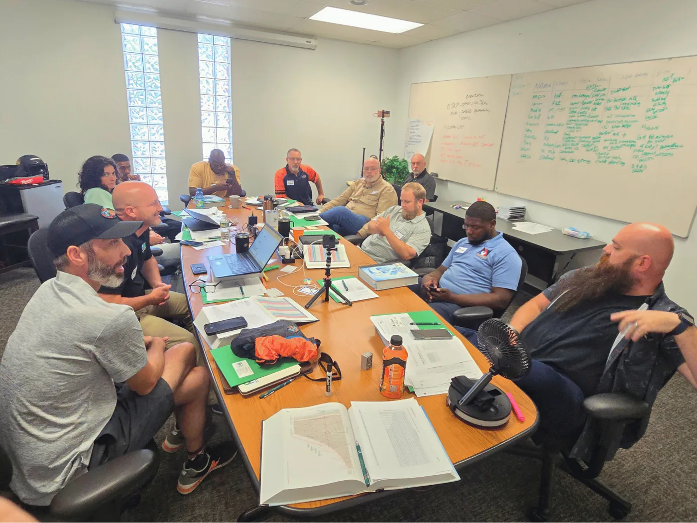 A training group around a conference table with a whiteboard of diagnostic notes