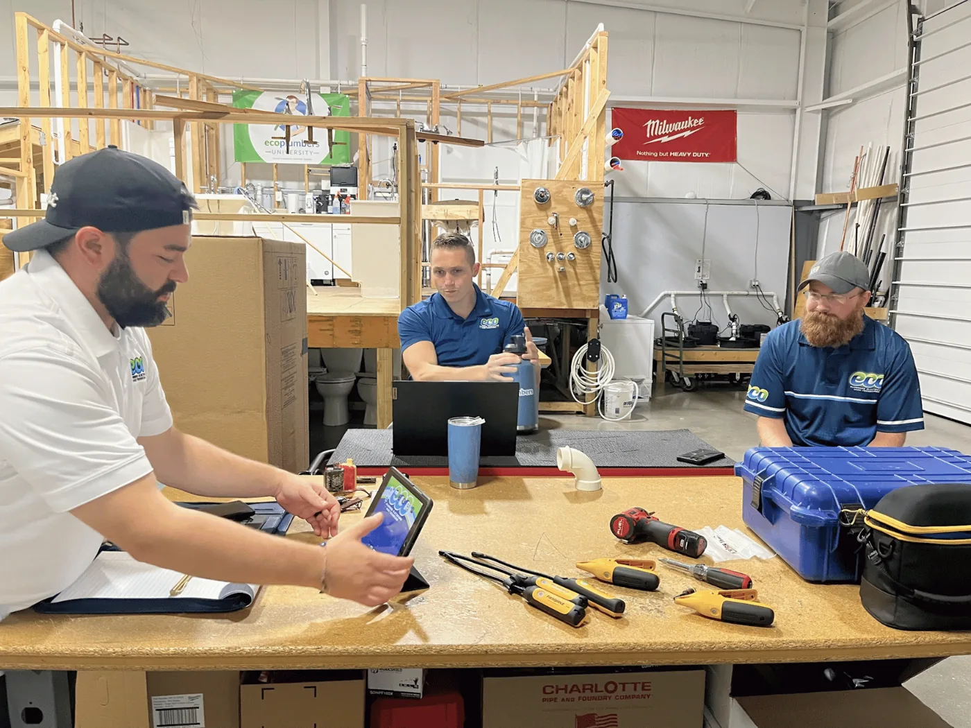 Technicians at a workbench reading a system on the measureQuick app, with probes and hand tools laid out