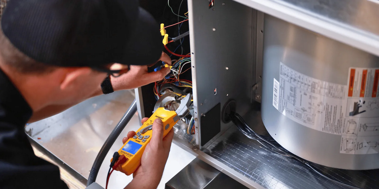 A technician using a Fieldpiece meter on a live air handler during hands-on training